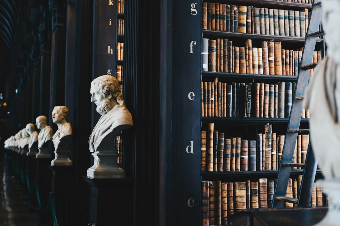 Biblioteca clásica con tomos jurídicos y bustos, símbolo de tradición académica